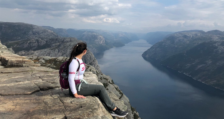 Girl sitting on the edge of the pulpit rock with the fjords underneath